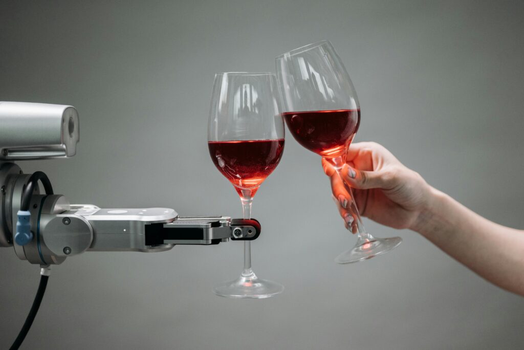 pexels-photo-8439094-8439094 A robot and a human hand clinking glasses of red wine, symbolizing technology and celebration.